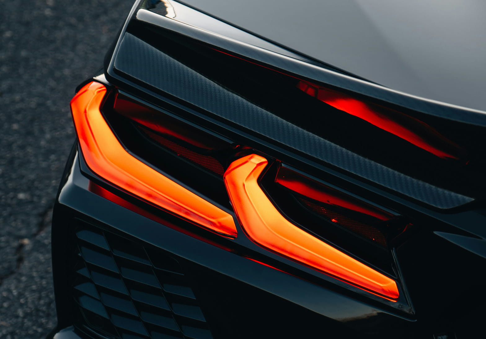 Close-up of a glowing red LED tail light on a black car