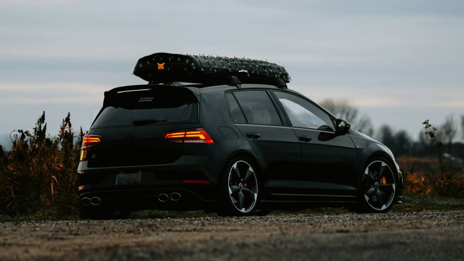 Black Volkswagen Golf with a roof cargo box parked outdoors