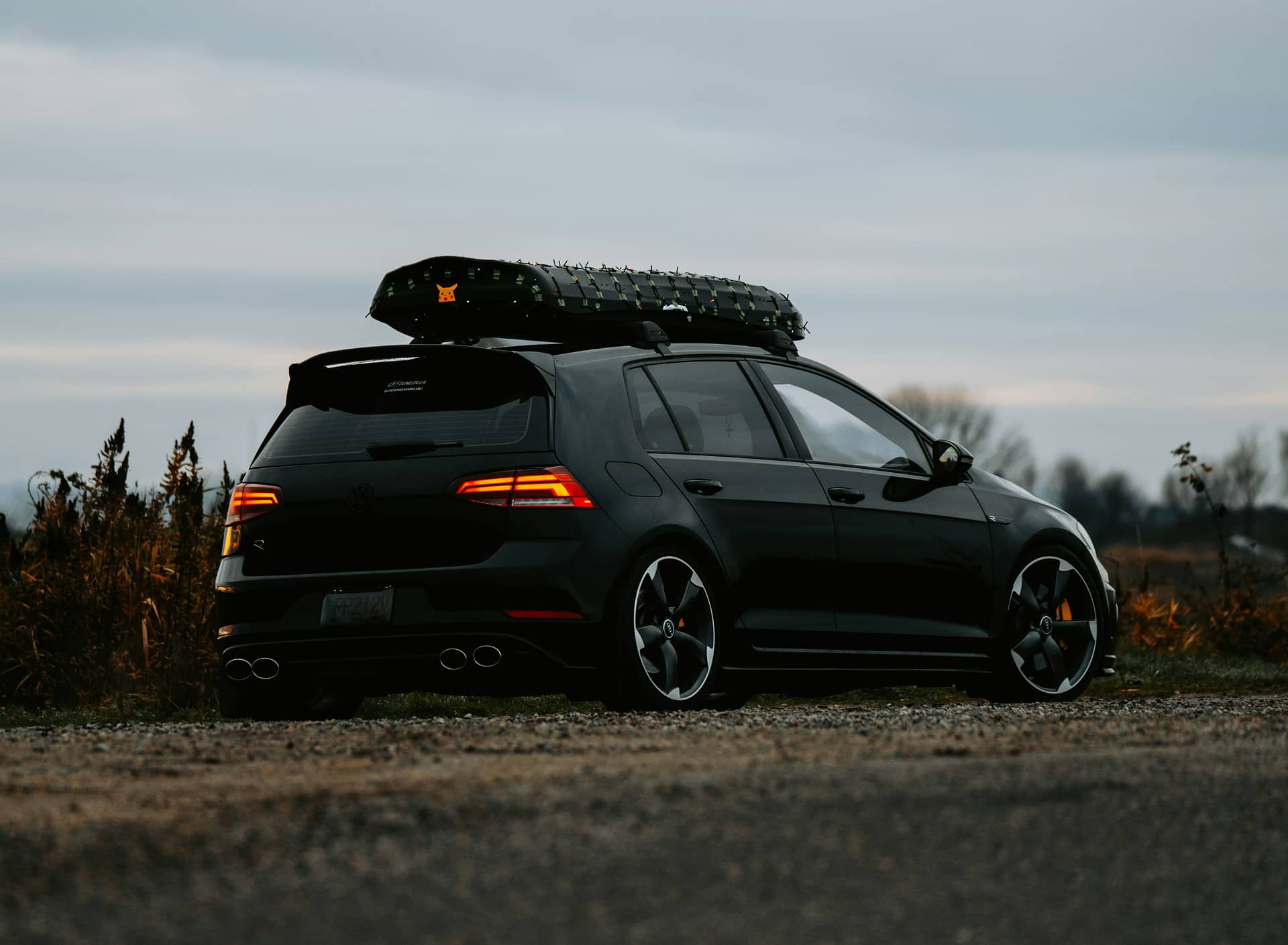 Black Volkswagen Golf with a roof cargo box parked outdoors