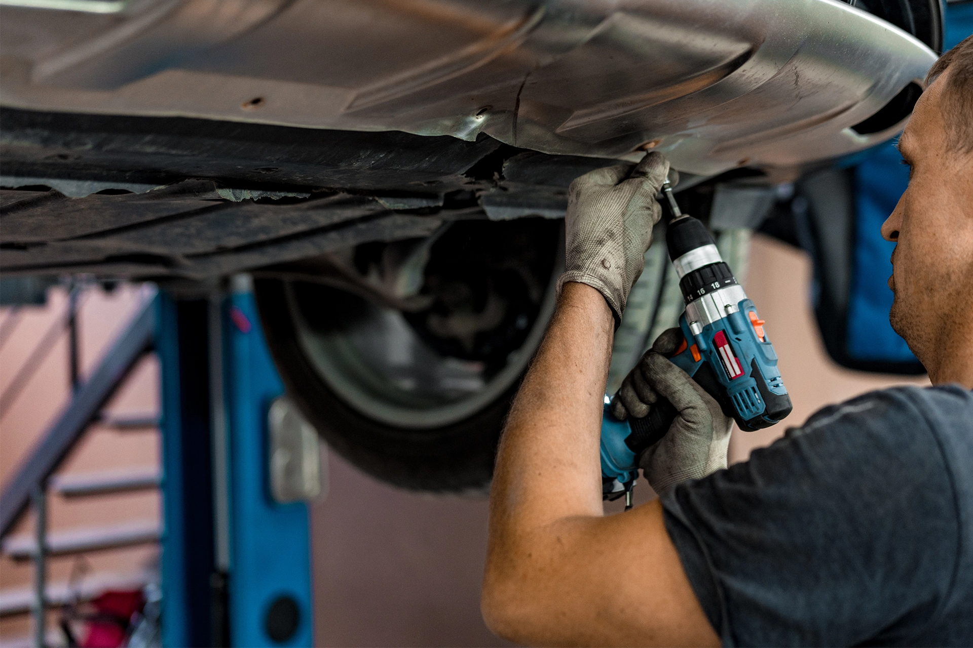 Mechanic drilling under a lifted car