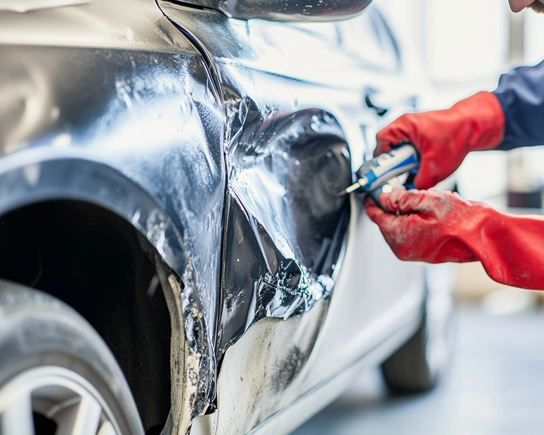 Technician repairing a dented car fender