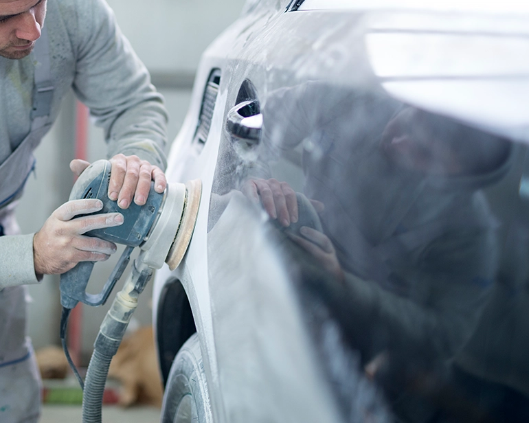 Technician sanding a car door panel