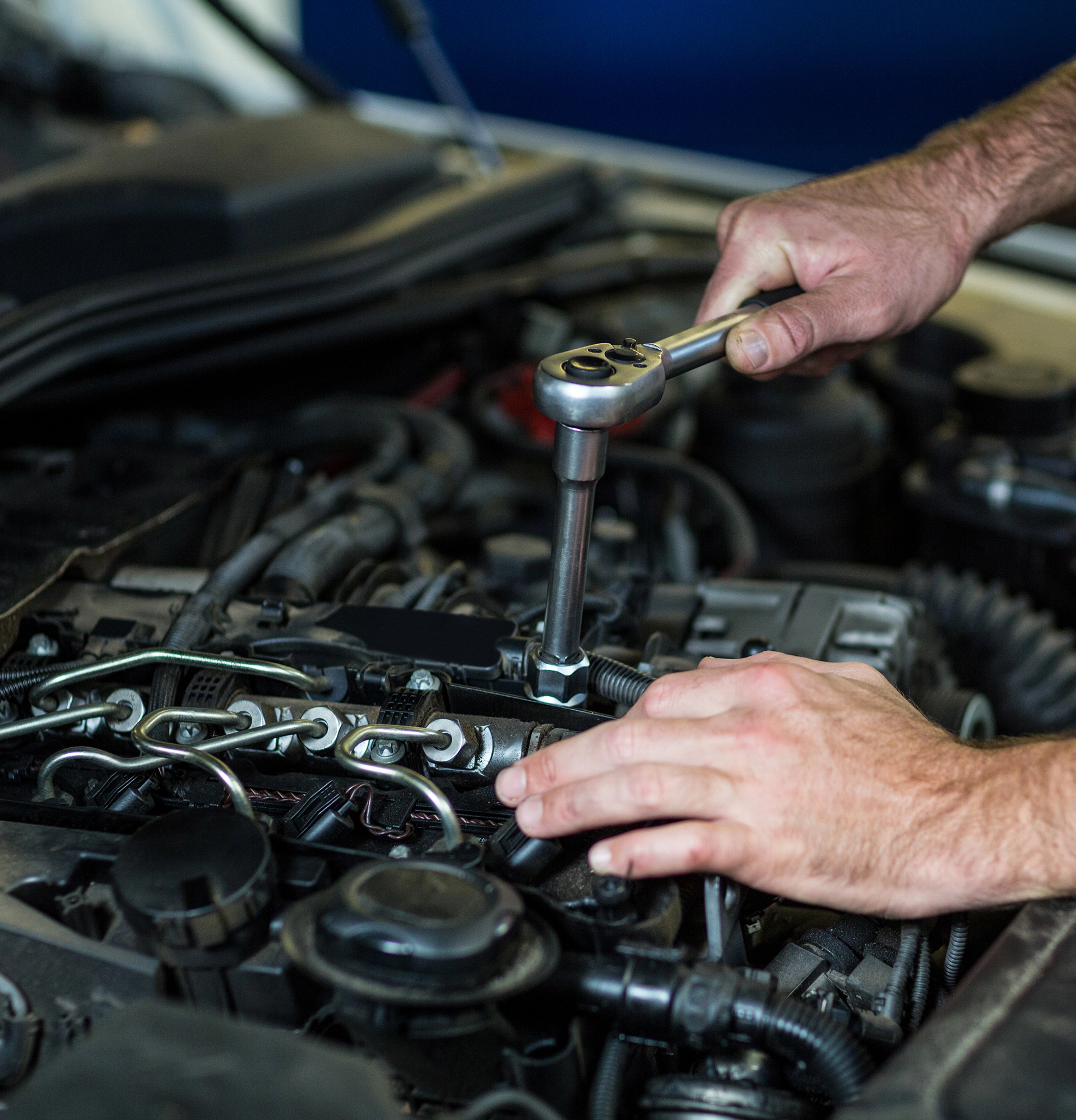 Mechanic using a ratchet wrench on a car engine