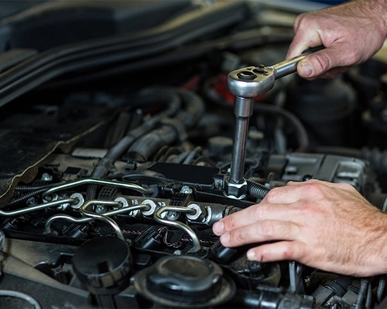 Mechanic using a ratchet wrench on a car engine