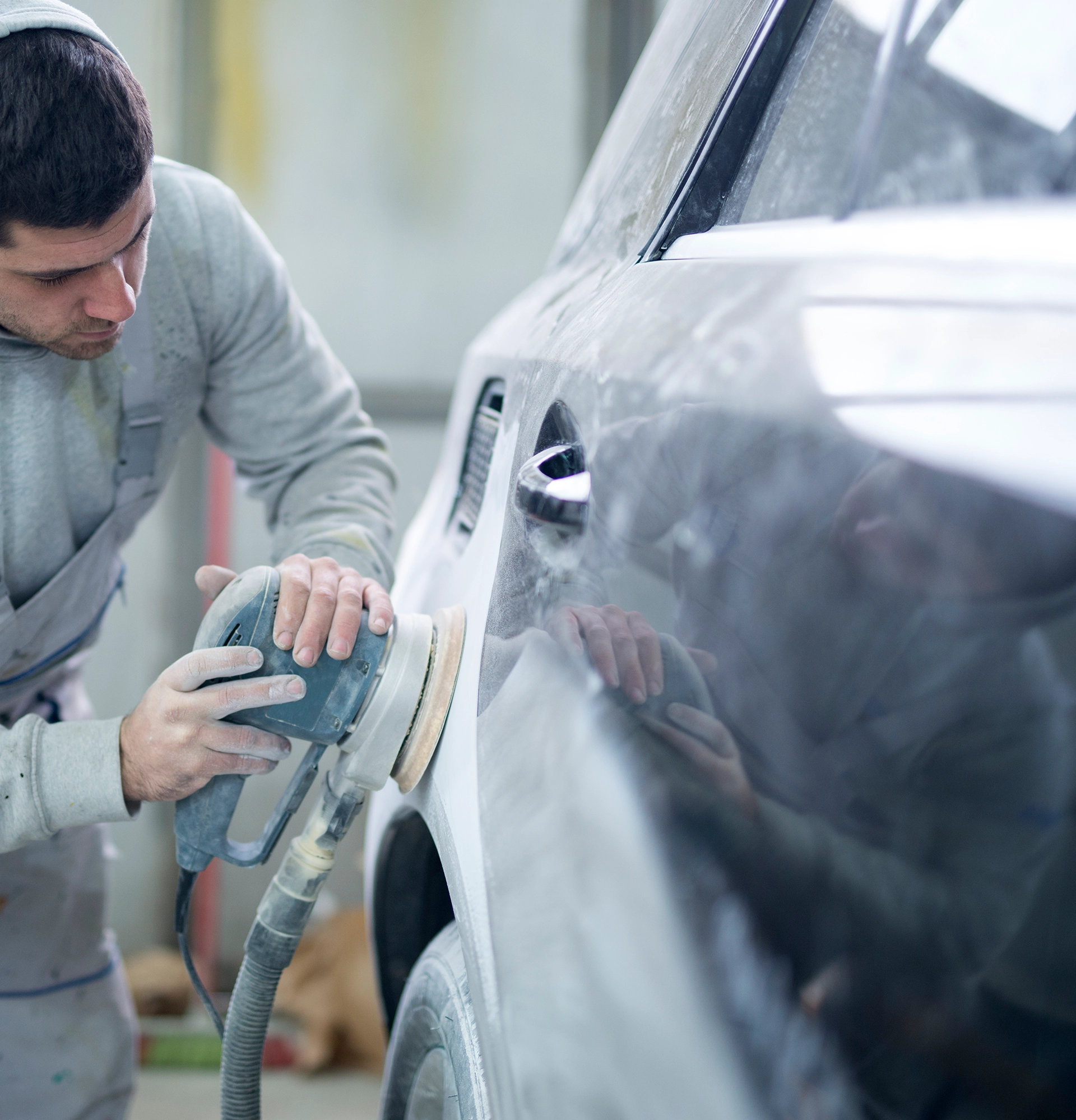 Technician sanding a car door panel