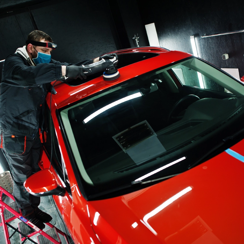 Detailer polishing the roof of a red car
